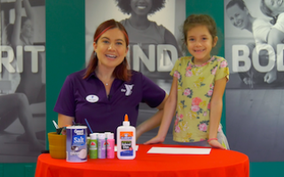 Y staff with young girl smiling with art supplies