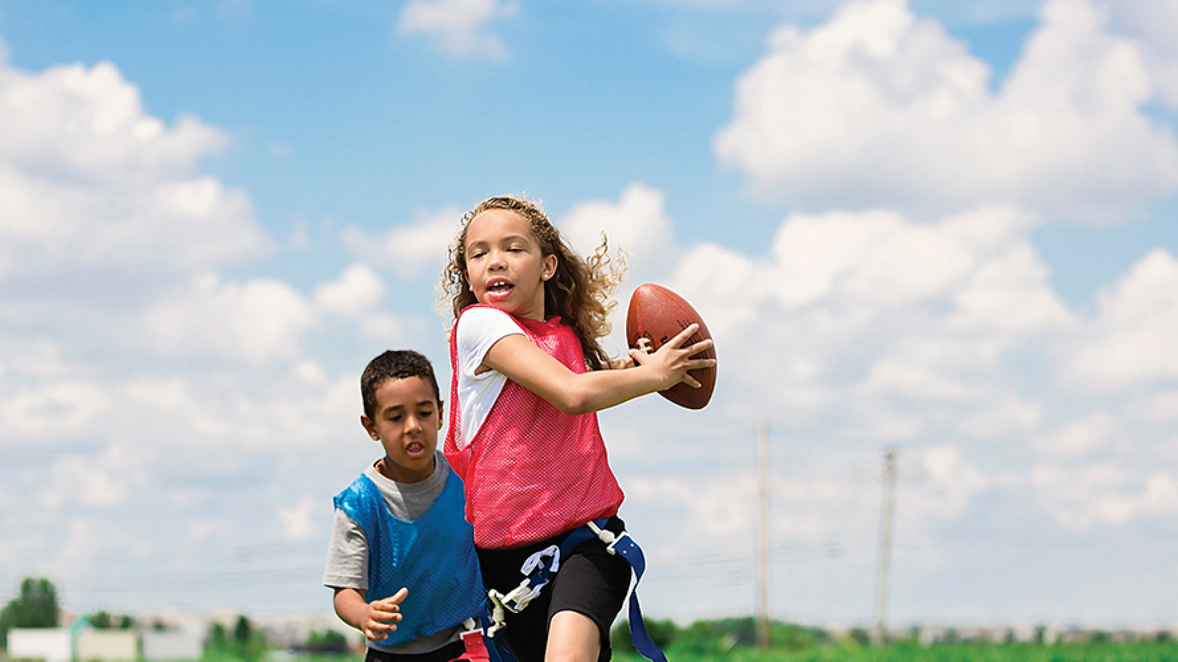 four kids playing flag football outside