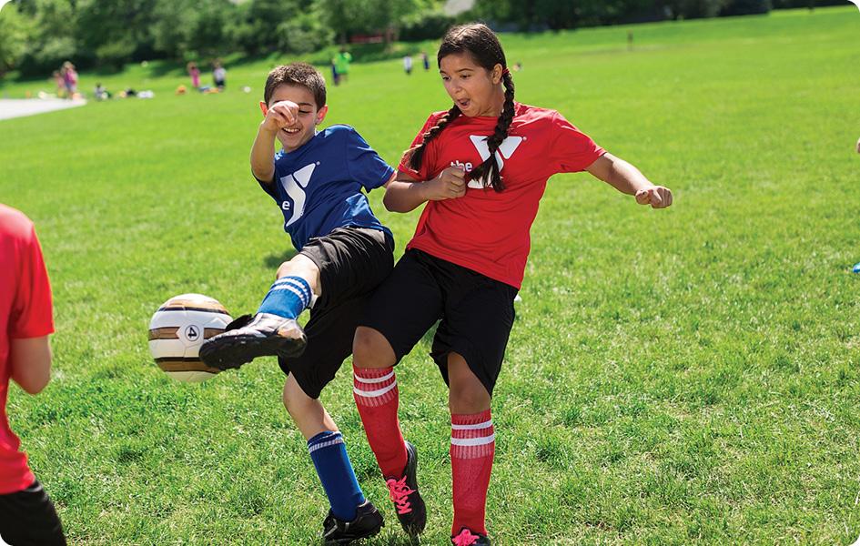 boy and girl smiling fighting for soccer ball