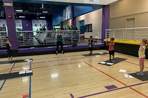 children standing on yoga mats in YMCA basketball gym