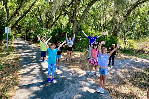 kids with arms up under trees