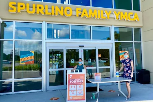 y staff members wearing masks in front of building entrance