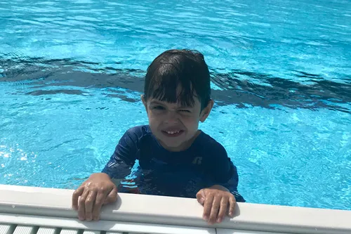kid holding onto edge of swimming pool