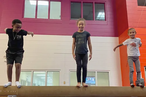 three kids standing on balance beam