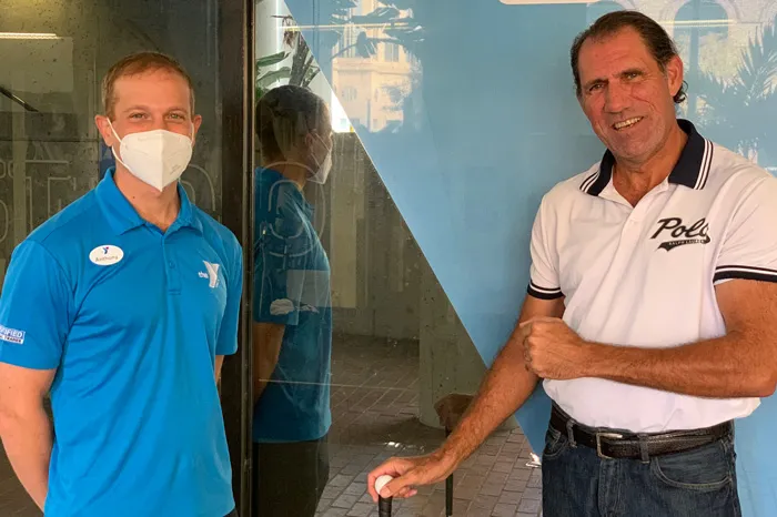 tampa ymca personal trainer wearing face covering and blue shirt next to man with golf ball 