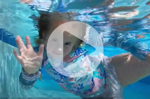 Girl swimming under water with a play button over photo