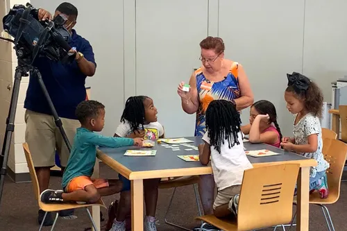 standing teacher talking with five kids sitting at table at Sulphur Springs K-8 Community School while Bay News 9 films