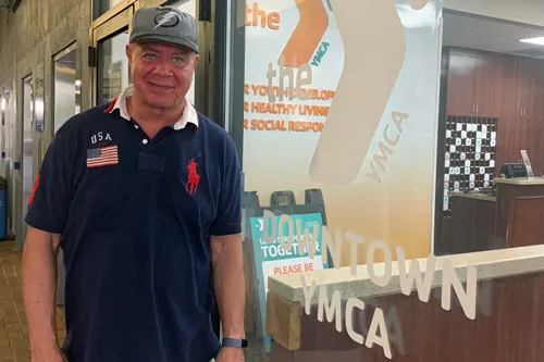 Arlie, wearing a hat and a navy polo, standing outside the Downtown Tampa YMCA