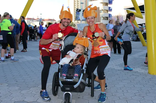 a man and woman pose with child in stroller at Tampa YMCA turkey gobble race, all wearing turkey hats