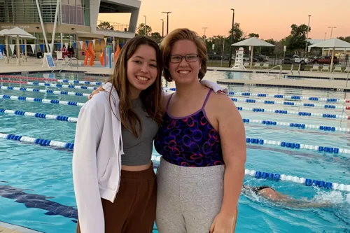 two volunteer swim instructors posing on outdoor pool deck