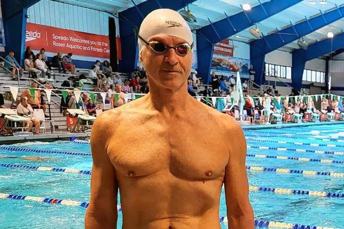 adult swimmer standing on pool deck at swim meet