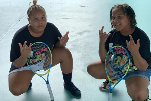 Sulphur Springs YMCA campers Amaya and Anaya, twins, pose with tennis rackets on the tennis court.