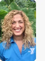 headshot of female personal trainer wearing blue YMCA polo plants background