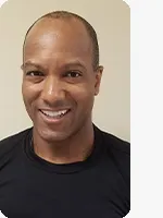 headshot of male personal trainer wearing black shirt beige background
