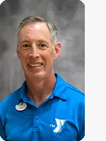 headshot male trainer wearing blue YMCA polo gray background