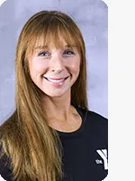 headshot of female trainer wearing black YMCA shirt gray background
