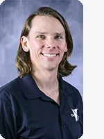 headshot of male personal trainer wearing black YMCA polo gray background