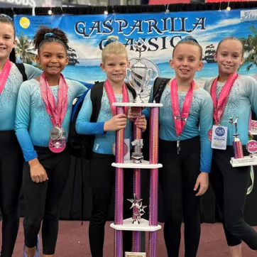 The 2023 Tampa Y Top Flight gymnastics team pose with their first place trophy at the Gasparilla Classic.
