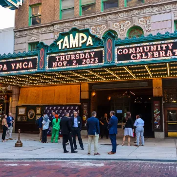 Group of people standing outside the Tampa Theater at dusk.